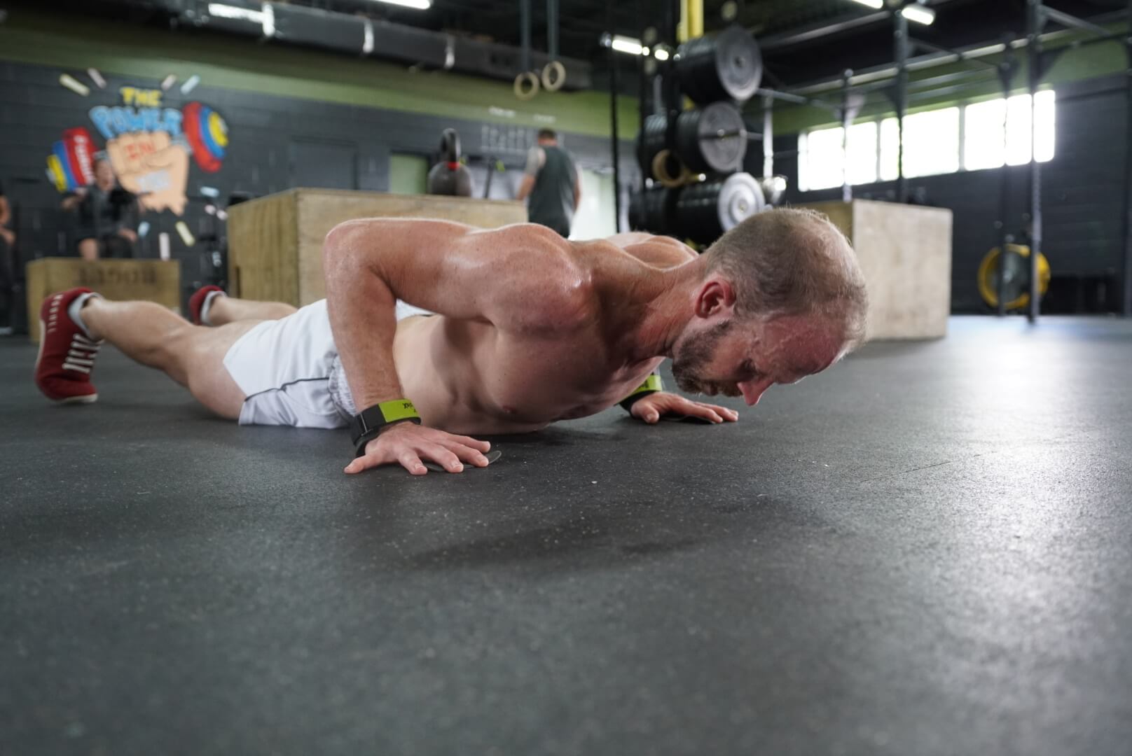 Crū Fitness gym in Ponchatoula, LA, fit co-owner Ron Pembo doing pushup in white shorts and red no bull crossfit shoes in gym