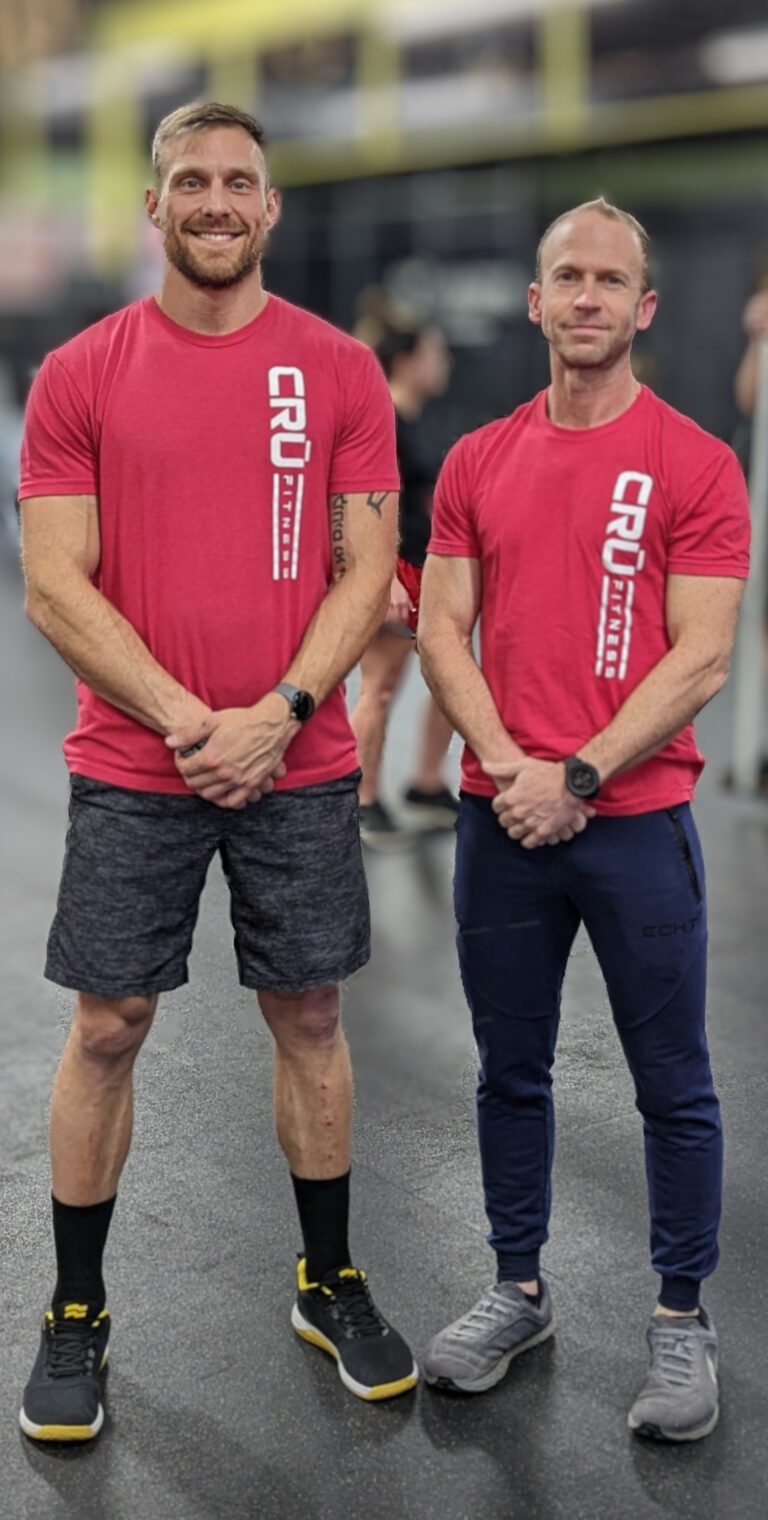 Cru Fitness CrossFit Gym owners Terry Veillon and Ron Pembo pose together in Red Cru t shirts inside the gym